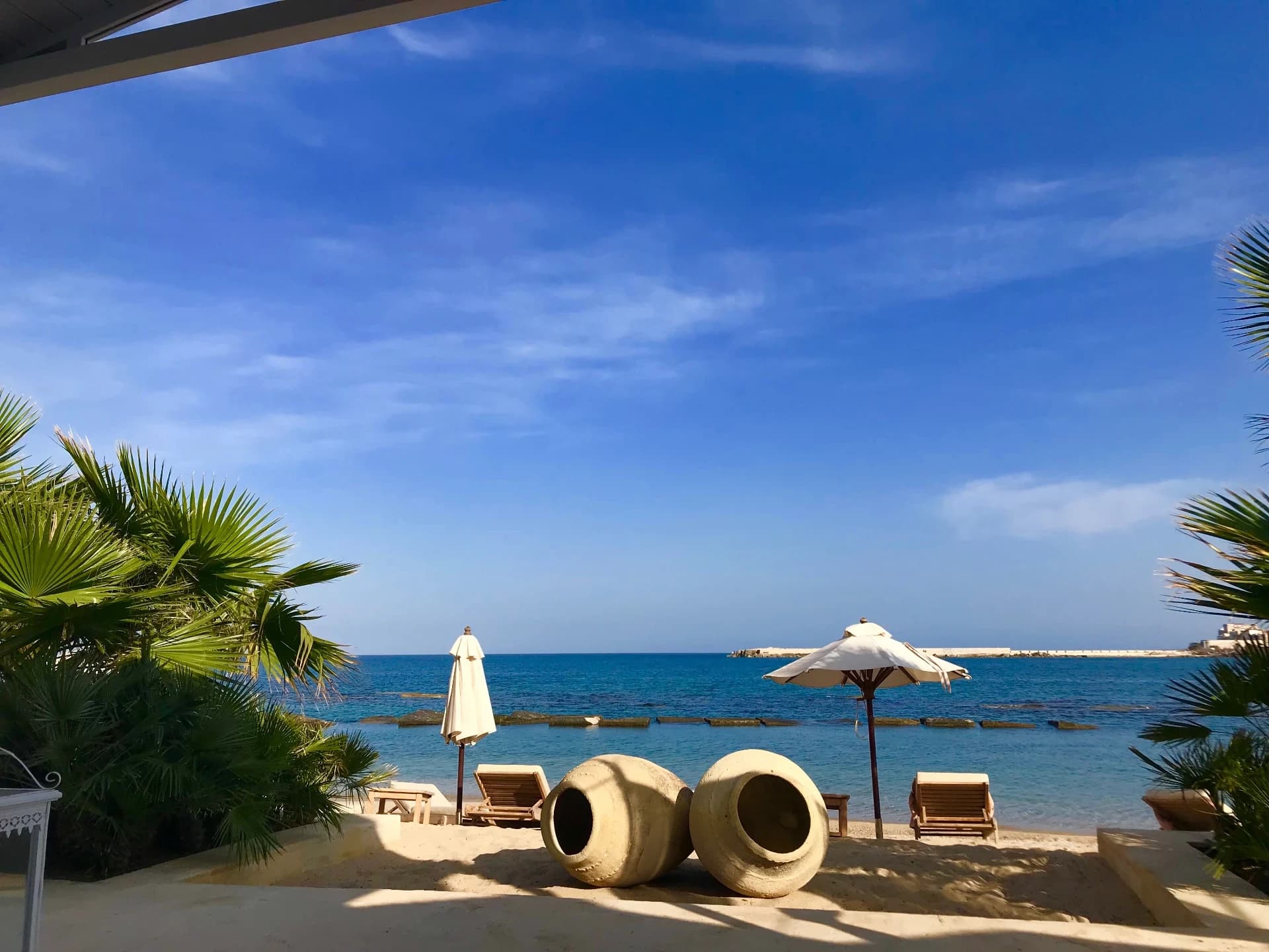 Sunbeds and stone amphorae on the rocky shore